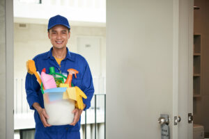 cheerful-asian-male-janitor-walking-into-hotel-room-carrying-supplies-bucket (1)